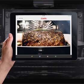 Un homme règle la température de son four à vapeur via son smartphone, grâce à l’application My AEG