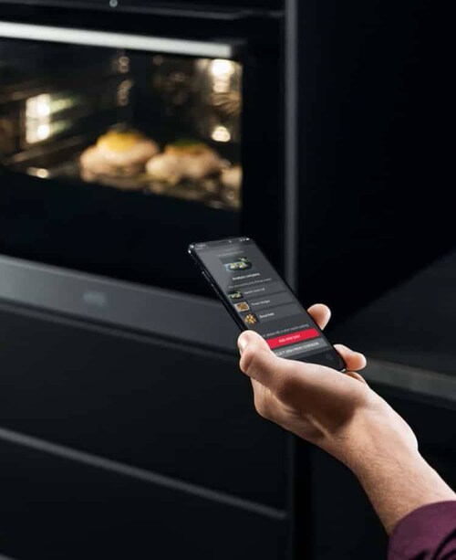 Une main avec un smartphone devant un four